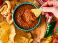 Une main trempe une chips dans une sauce salsa maison. Parfait pour une sauce salsa recette rapide et savoureuse.