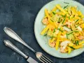 Salade colorée avec des crevettes, de l'avocat et des bâtonnets de mangue, garnie de ciboule. Un délice frais et fruité.
