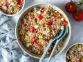 Un grand bol de salade de riz thon, garnie de tomates, maïs et œufs durs. Parfait pour un repas frais et léger.