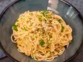Un plat de pâtes au thon, garni de persil frais et de poivre noir, servi dans un bol bleu.