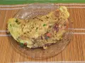 Une savoureuse omelette mexicaine garnie d'oignons rouges, de poivrons et d'herbes fraîches, servie sur une assiette en verre.