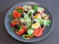 Salade niçoise colorée avec tomates, concombres, œufs, olives noires et anchois.