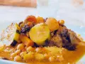 Un plat généreux de couscous algérien avec légumes, pois chiches, raisins secs et viande mijotée dans une sauce savoureuse.