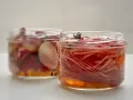 Deux bocaux de pickles d'oignon rouge, l'un avec des oignons entiers, l'autre avec des lamelles fines, baignant dans une marinade ambrée.