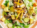Salade Big Mac avec laitue, bœuf haché, fromage râpé, croûtons et cornichons, arrosée d'une sauce crémeuse.