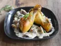 Deux pilons de poulet dorés baignent dans une sauce crémeuse aux champignons, garnie d'herbes fraîches. Un délice de poulet à la crème.