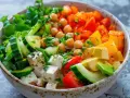 Un bol coloré de salade fraîche avec pois chiches, concombre, tomates, poivrons, avocat et feta. Parfait pour savoir que manger froid.