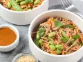 Pâtes soba aux edamames, carottes râpées et coriandre, servies avec une sauce crémeuse. Un délice sain et coloré.