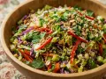 Salade asiatique colorée dans un bol en bois, garnie de cacahuètes, d'amandes effilées et de graines de sésame.