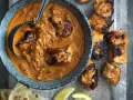 Un plat de poulet tikka savoureux, avec des morceaux de poulet grillés dans une sauce crémeuse et des accompagnements comme du pain naan et des quartiers de citron.