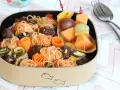 Bento box avec spaghetti et boulettes, garni de courgettes et carottes roulées. Une brochette de fruits complète cette idée repas à emporter au travail.