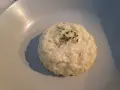 Un crémeux risotto coco, parsemé de ciboulette fraîche, repose sur une assiette claire.