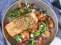 Un filet de saumon croustillant, garni de graines, servi avec des pommes de terre rôties et une salade verte. Un accompagnement poisson savoureux et coloré.