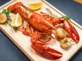 Homard entier, prêt pour la cuisson, garni de citron, d'oignons grillés et d'ail. Un délice pour les amateurs de fruits de mer.