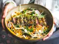 Un délicieux tataki de thon, enrobé de sésame, servi avec un accompagnement coloré de légumes croquants et de pousses fraîches.
