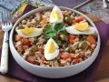 Salade de thon, haricots, tomates et olives, garnie d'œufs durs. Une idée repas facile et rapide.