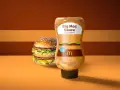 Bouteille de sauce Big Mac en édition limitée à côté d'un Big Mac. La sauce a un design inspiré du burger.