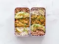 Deux lunch box remplies d'une idée lunch box école saine : curry de légumes, riz, pois chiches et avocat.