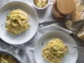 Deux assiettes de pâtes crémeuses à l'ail, garnies de persil frais. Un pain croustillant et du fromage râpé complètent cette recette de pâtes à l'ail et crème.