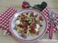 Une savoureuse salade italienne de pâtes avec tomates cerises, mozzarella, olives et jambon cru, garnie de ciboulette.