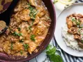 Poulet en sauce tomate séchée crème, garni de basilic frais, servi dans une poêle et sur une assiette de riz.