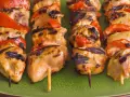 Brochettes de poulet grillé avec poivrons rouges sur une assiette verte. Parfait pour savoir quoi servir avec des brochettes de poulet.
