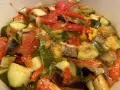 Un plat coloré de ratatouille niçoise, avec des morceaux de courgettes, aubergines, tomates et poivrons mijotés.