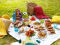 Un pique-nique gourmand sur l'herbe : pains, fromages, fruits, mini quiches, sandwichs, roulé salé, et boissons colorées. Une belle idée pique-nique !