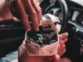 Une main attrape des mûres et des myrtilles dans une barquette, prêt à manger dans sa voiture le midi.