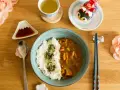 Un délicieux curry japonais avec du riz blanc, servi avec une tasse de thé et des décorations mignonnes.