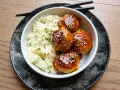 Délicieuses boulettes de poulet asiatique nappées d'une sauce sucrée et salée, servies avec du riz blanc et parsemées de graines de sésame.