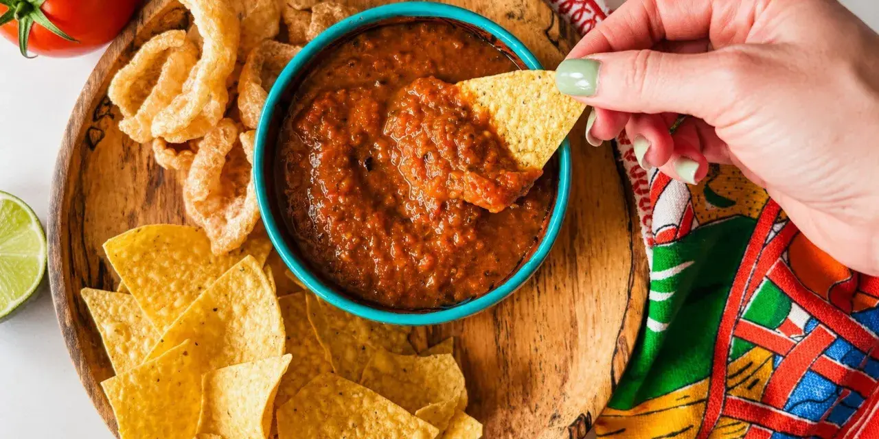 Une main trempe une chips dans une sauce salsa maison. Parfait pour une sauce salsa recette rapide et savoureuse.