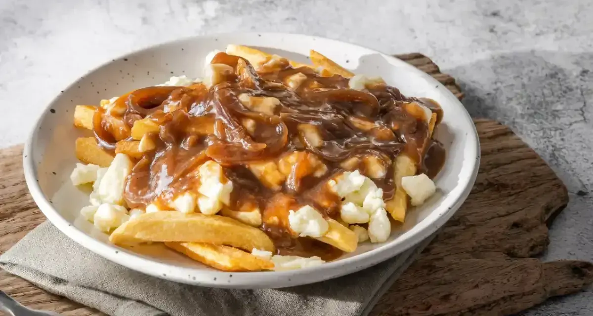 Une assiette de poutine fumante, parfaite pour une recette poutine maison facile. Des frites croustillantes, du fromage en grains et une sauce brune onctueuse.