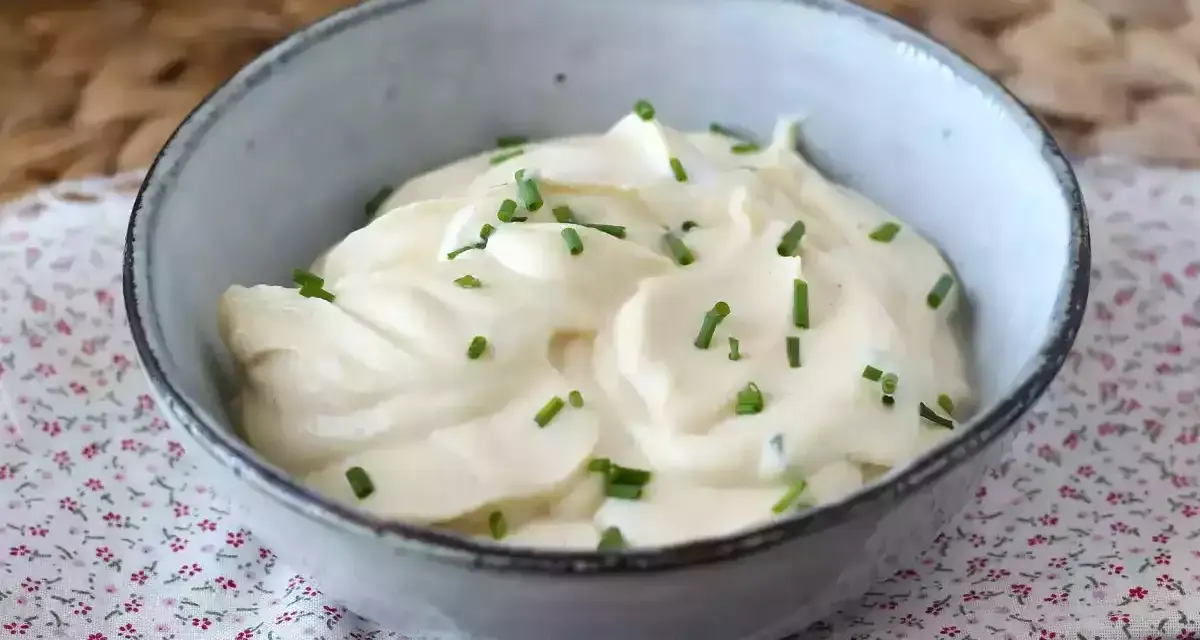 Mayonnaise sans huile crémeuse, garnie de ciboulette fraîche, dans un bol en céramique. Parfait pour un repas léger.