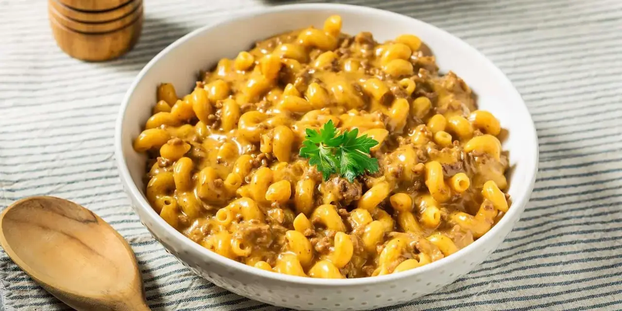Un bol de macaroni au fromage crémeux avec du bœuf haché, garni de persil. Un plat parfait pour un dîner rapide et facile.