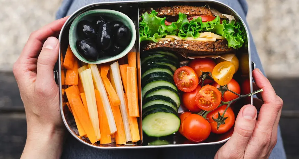 Un bento sain avec sandwich, bâtonnets de carottes et céleri, tomates cerises, concombres et olives noires.