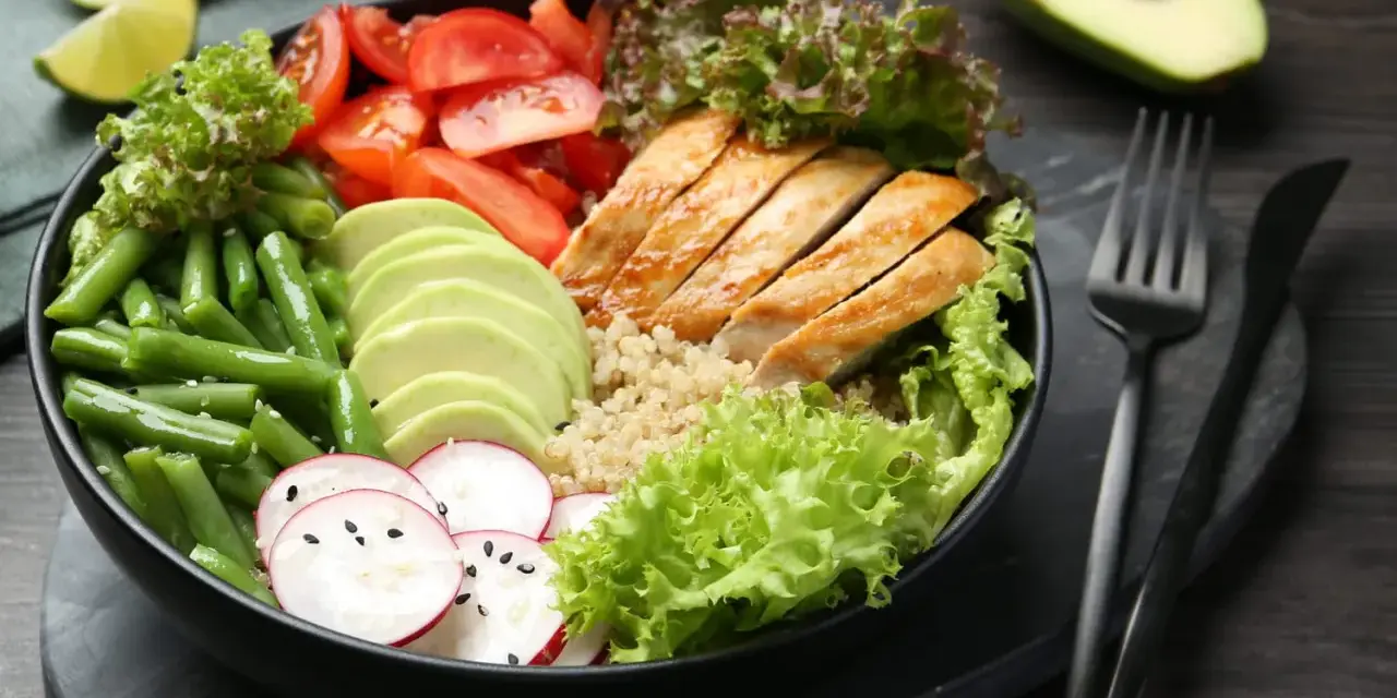 Un bol coloré avec poulet grillé, avocat, haricots verts, tomates et radis. Une idée de recette souper saine et équilibrée.
