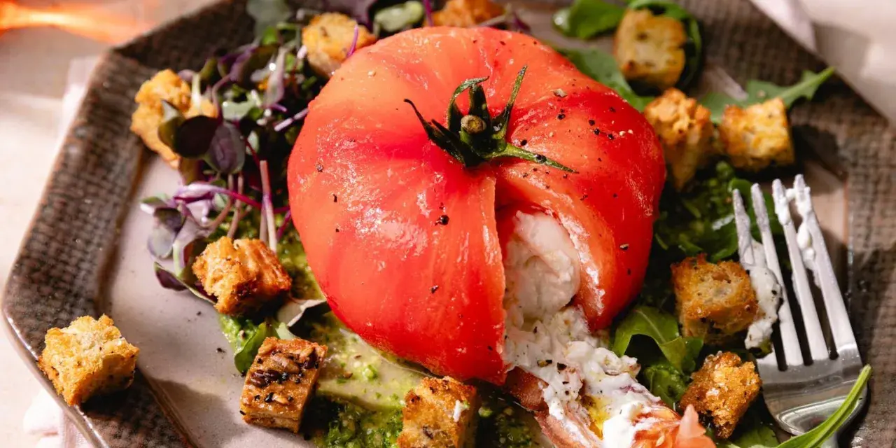 Une tomate farcie de burrata crémeuse, accompagnée de croûtons croustillants et d'une sauce verte. Une idée parfaite pour une recette burrata froide.