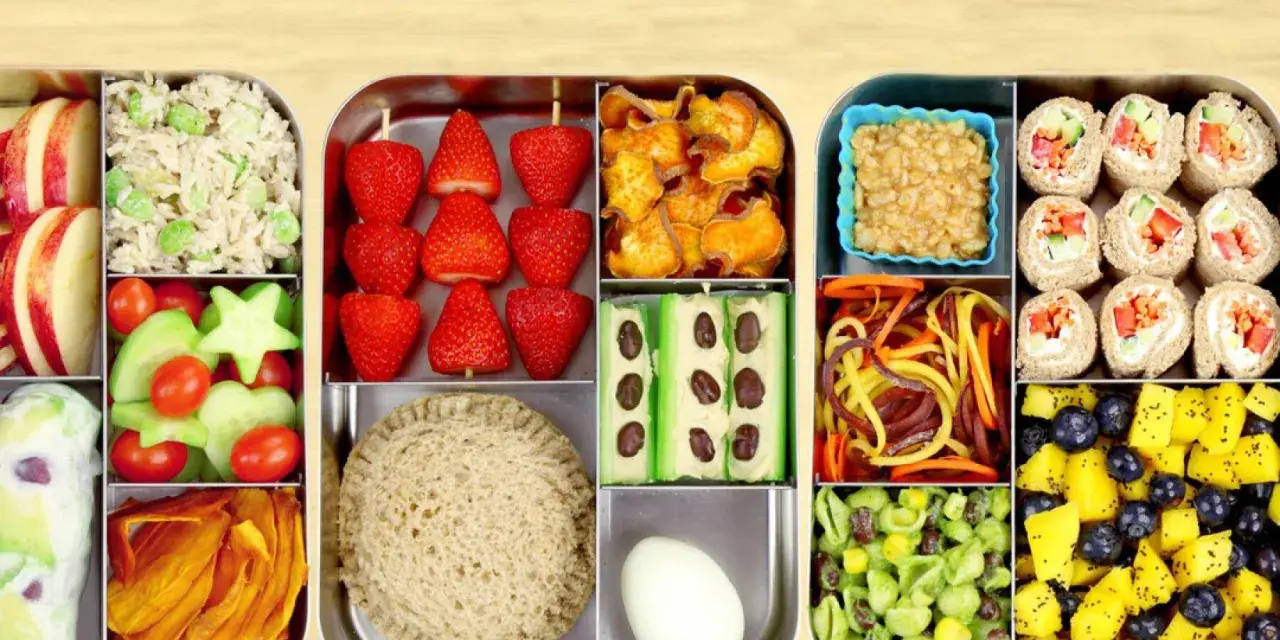 Une recette bento colorée et équilibrée : riz, fraises, crudités, sandwich, rouleaux de printemps, fruits et légumes variés.