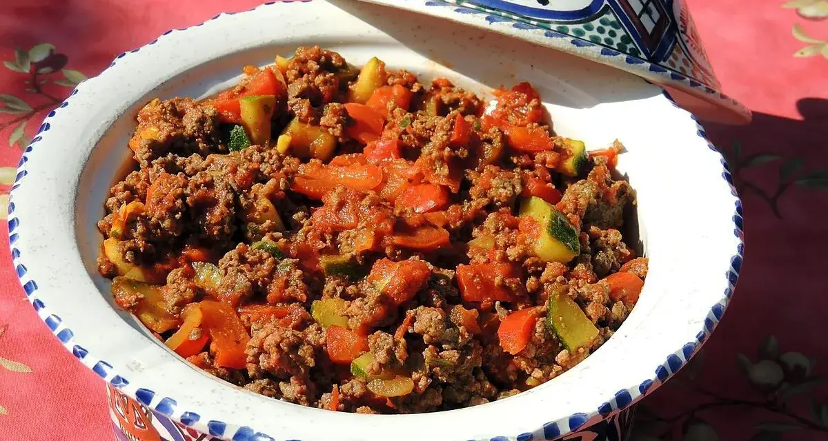 Un plat savoureux de recette viande hachée avec des légumes, servi dans un plat à tajine décoré.
