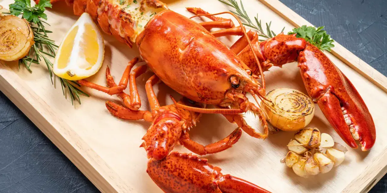 Homard entier, prêt pour la cuisson, garni de citron, d'oignons grillés et d'ail. Un délice pour les amateurs de fruits de mer.