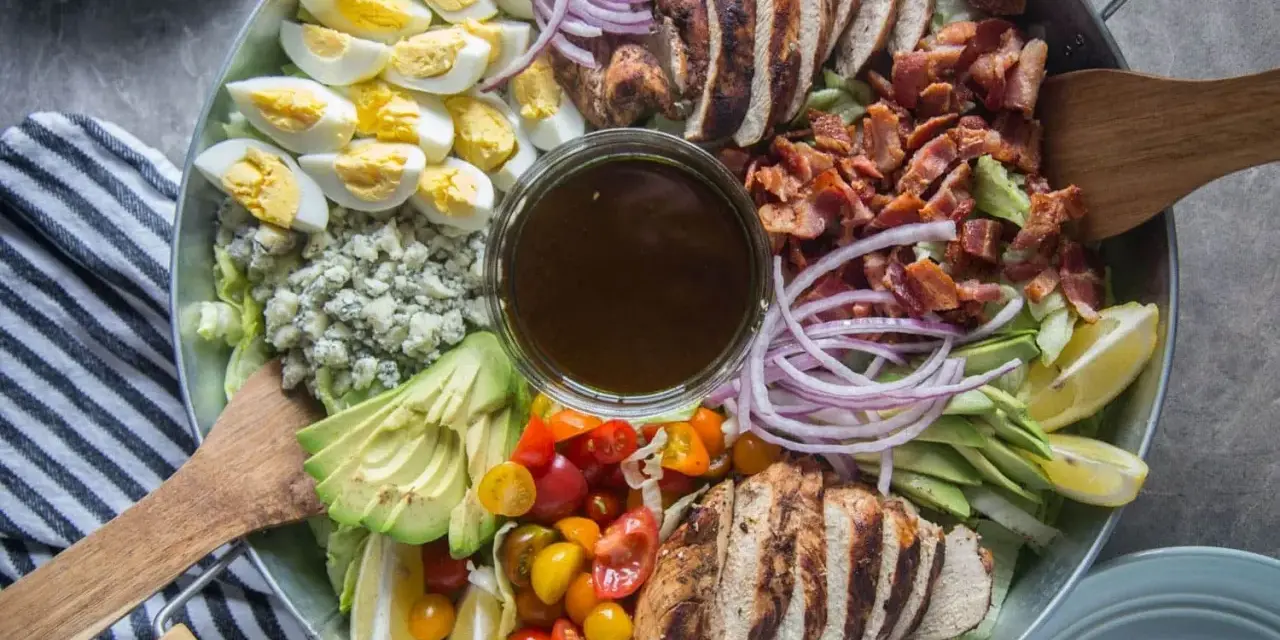 Salade généreuse avec poulet grillé, bacon croustillant, œufs durs, avocat, tomates cerises, oignons rouges et fromage bleu. Une salade kobe parfaite pour un repas complet.