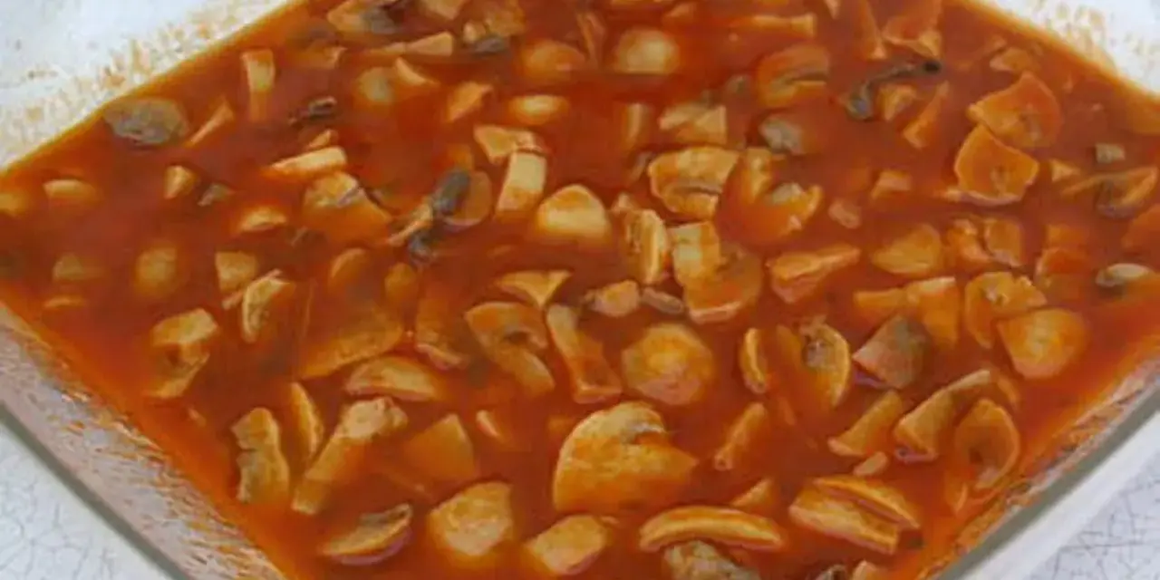 Champignons à la grecque, une préparation savoureuse de champignons coupés en morceaux, mijotant dans une sauce tomate riche et parfumée.