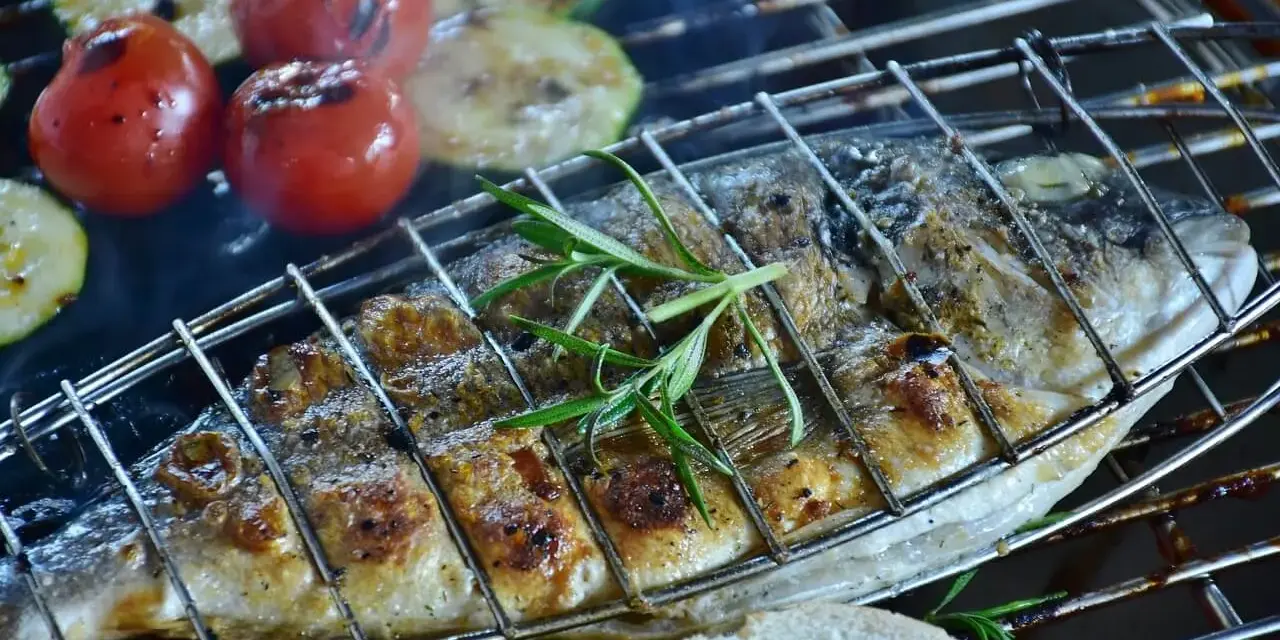 Dorade au barbecue, grillée à la perfection avec des tomates et courgettes, garnie de romarin. Un délice estival.