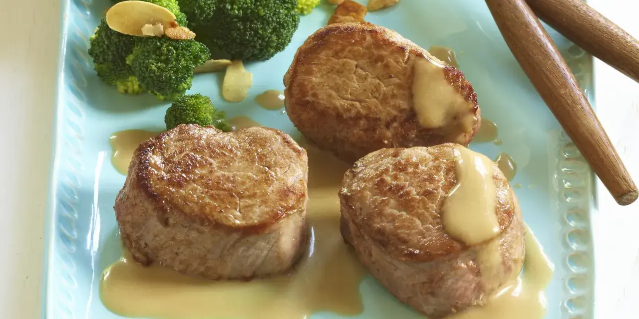 Trois médaillons de porc tendres nappés d'une onctueuse sauce moutarde, accompagnés de brocolis croquants. Un délice pour les amateurs de viande de porc.