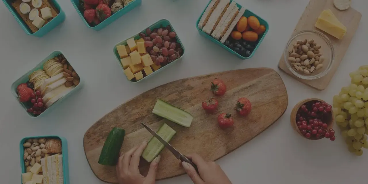 Préparation d'un panier repas travail de nuit : fruits, légumes, sandwichs, œufs, fromage et noix.