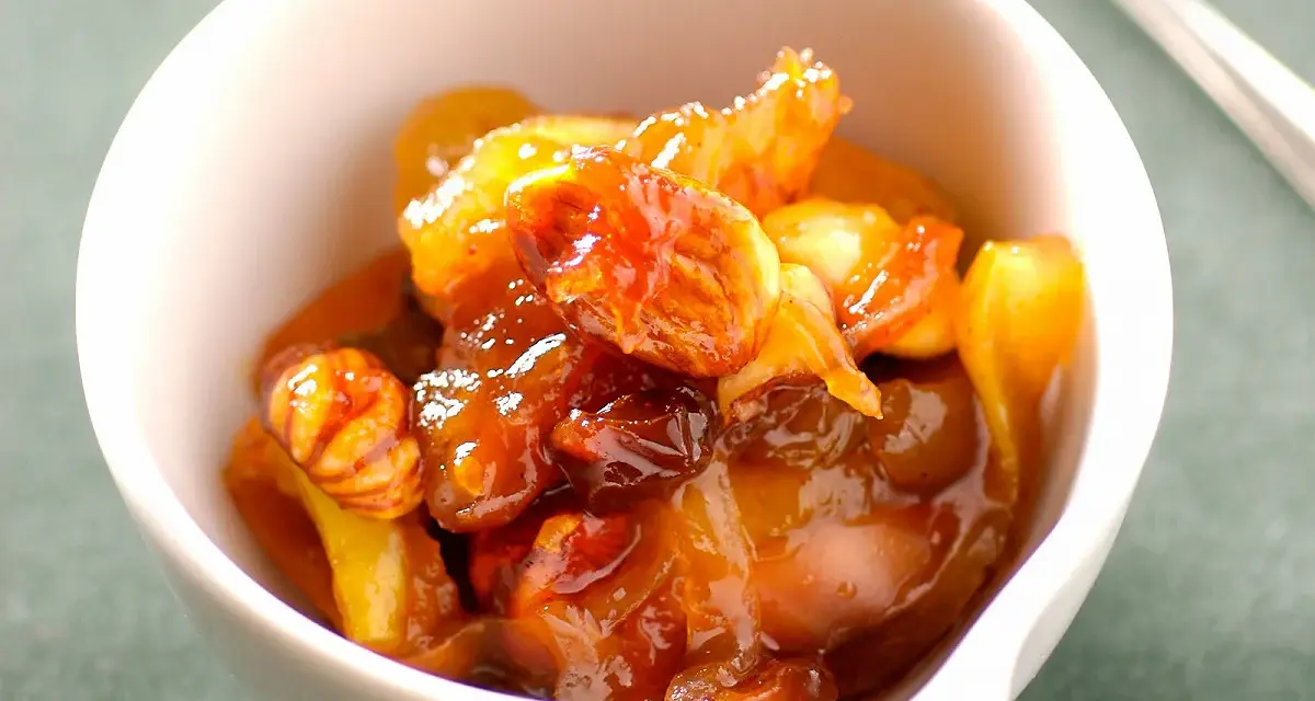 Chutney de prunes, un délice sucré-salé aux fruits confits et noix, servi dans un bol blanc.
