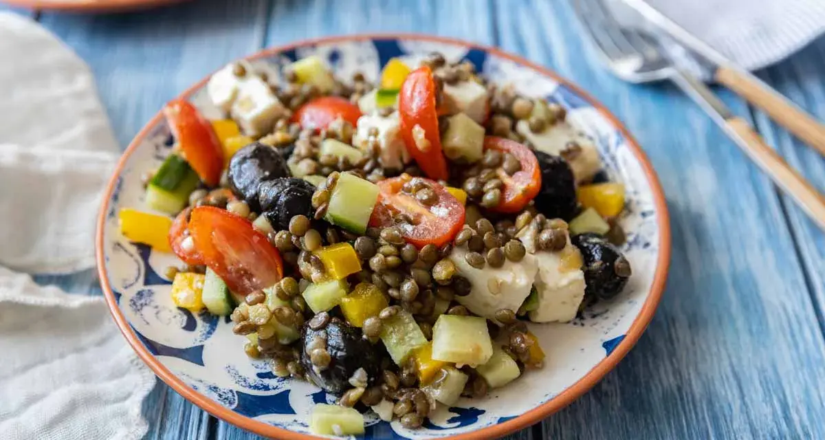 Salade de lentilles colorée avec tomates, concombre, poivrons, olives noires et feta. Un plat frais et savoureux.