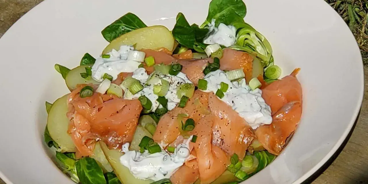 Salade nordique appétissante : saumon fumé, pommes de terre, salade verte et sauce crémeuse aux herbes. Parfait pour un repas léger.
