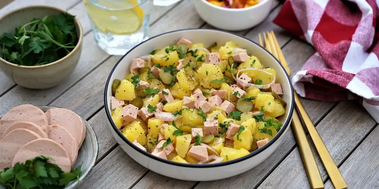 Salade strasbourgeoise appétissante avec pommes de terre, saucisse en dés, cornichons et persil frais. Un délice alsacien !